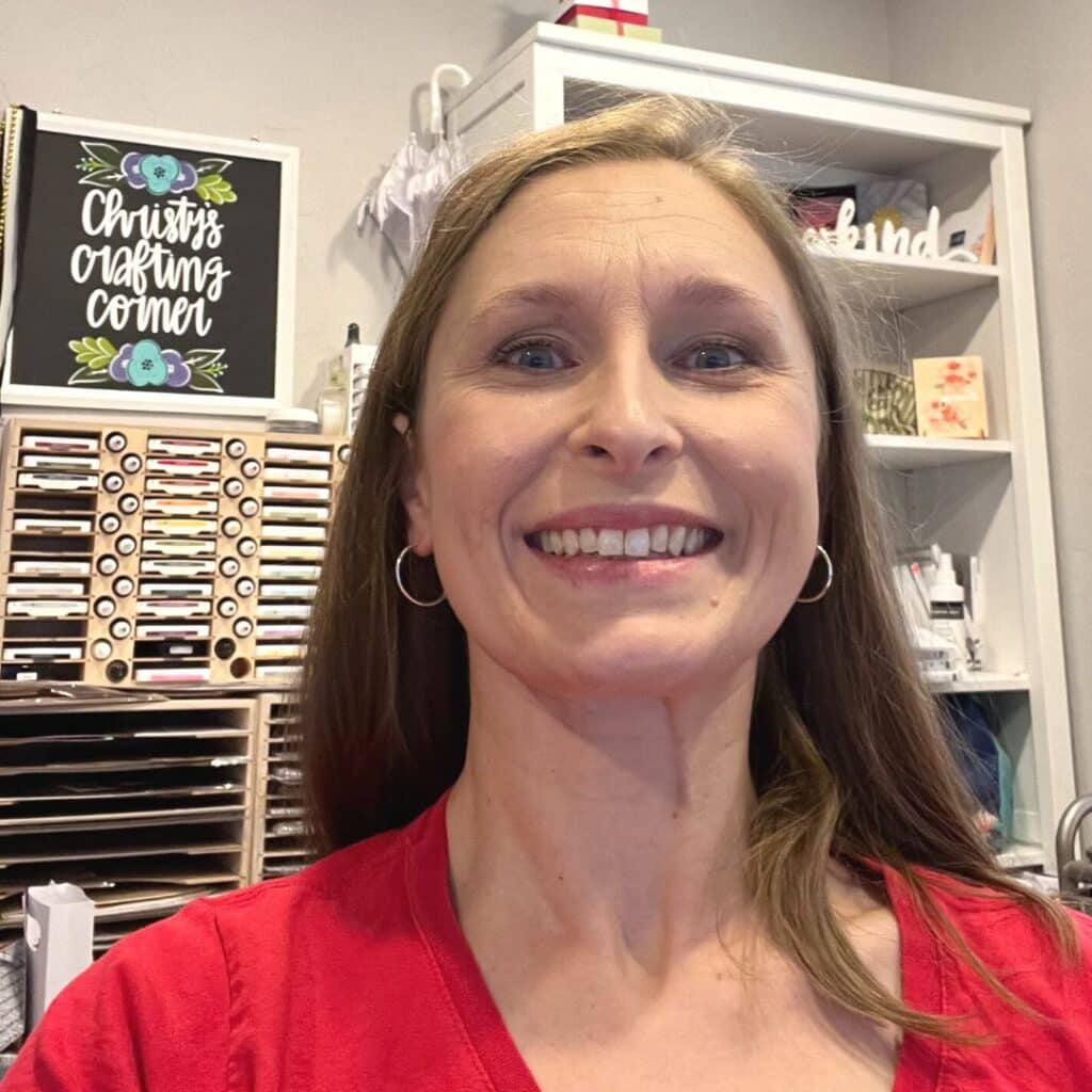 Christy Hillock wearing a red shirt smiling while working in craft room